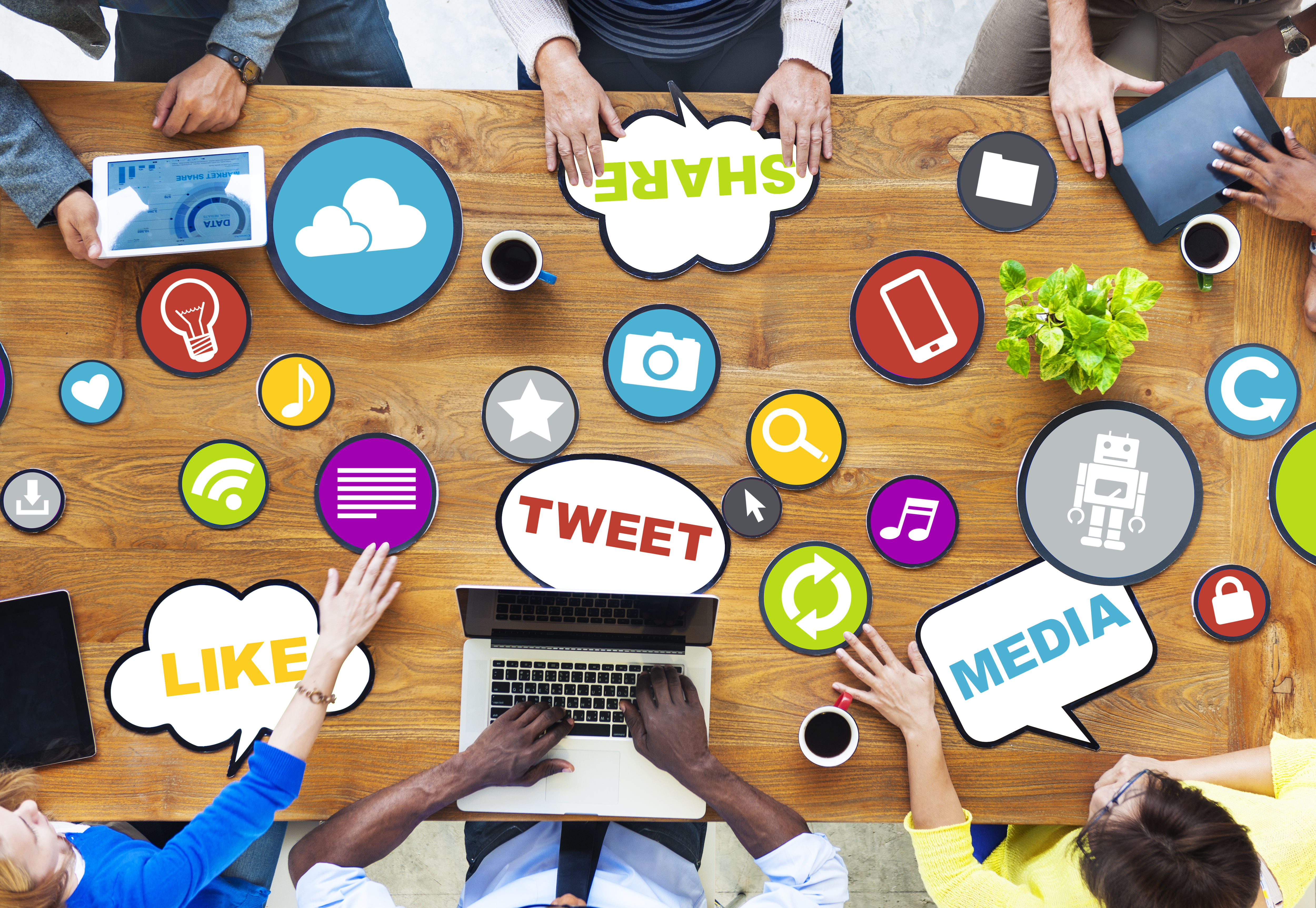 desktop with app icons ontop, 6 people surrounding the desk, with electronics in hands